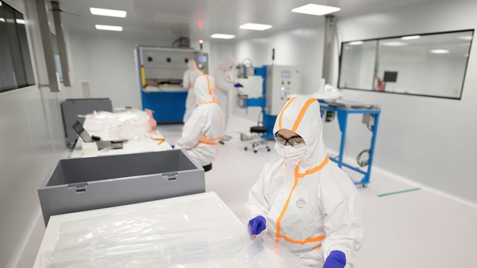 Workers in protective suits inside a pharmaceutical cleanroom