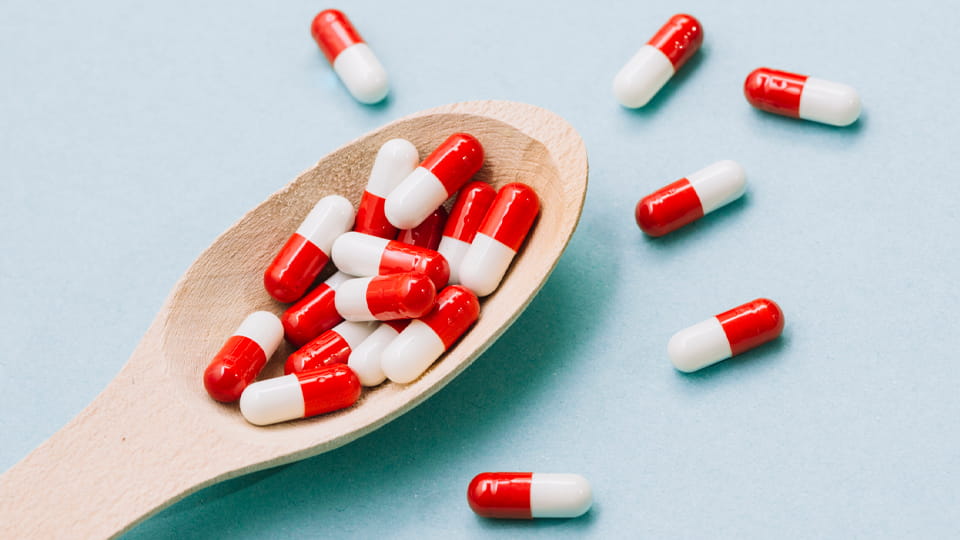 tahta kaşık üzerinde kırmızı-beyaz sert jelatin kapsüller