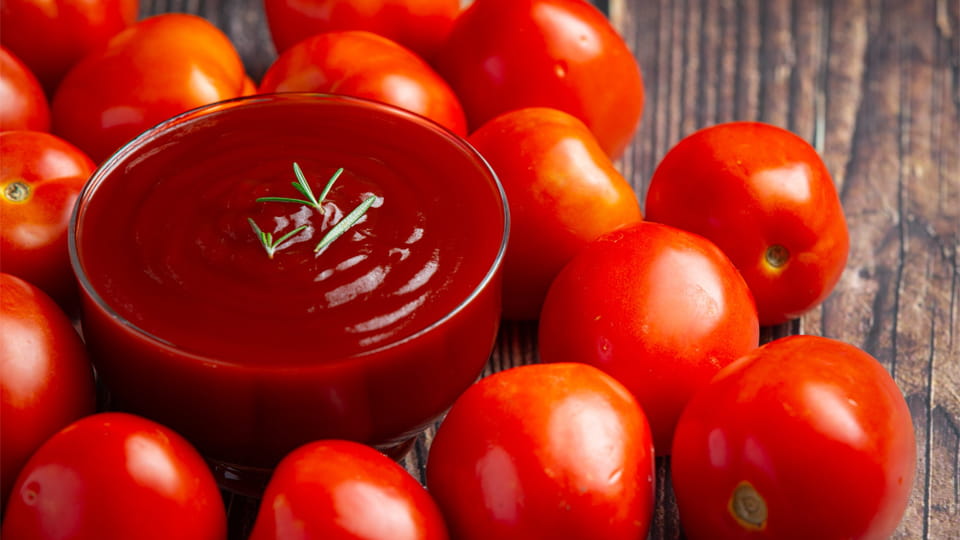 Ketchup in bowl with fresh tomato