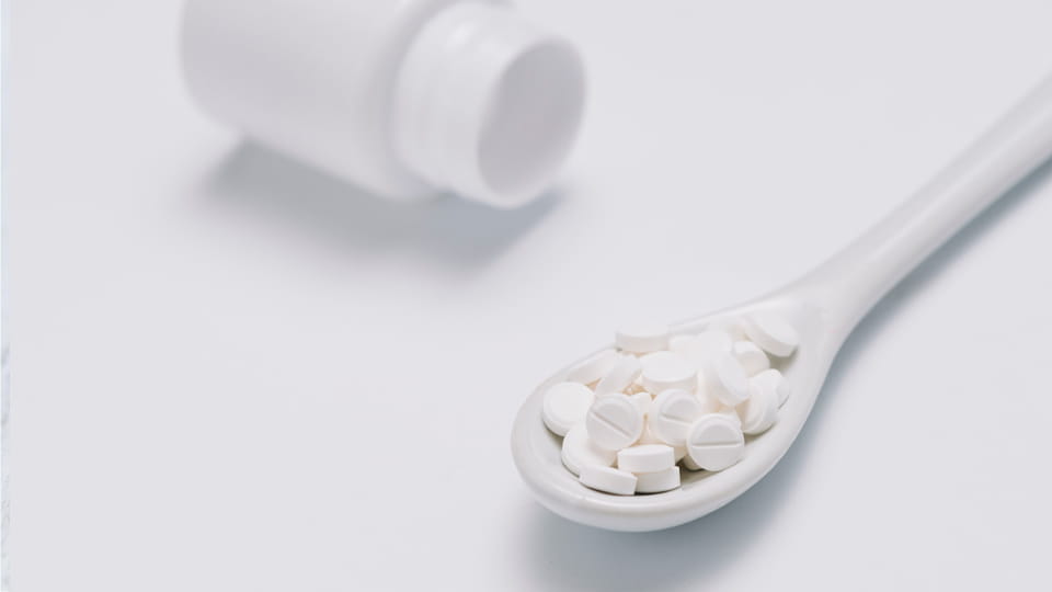 White tablets on spoon with bottle