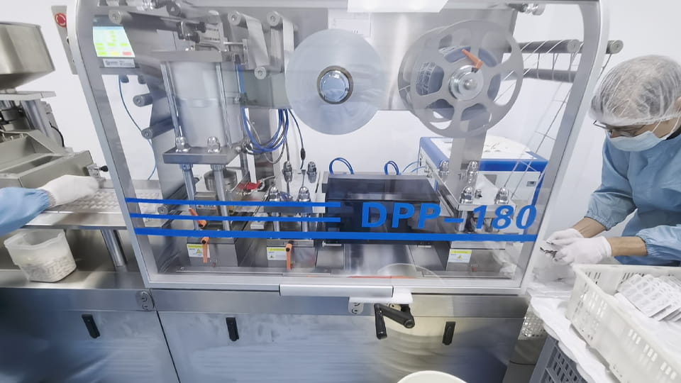 Operators inspecting pills at a pharmaceutical packaging line