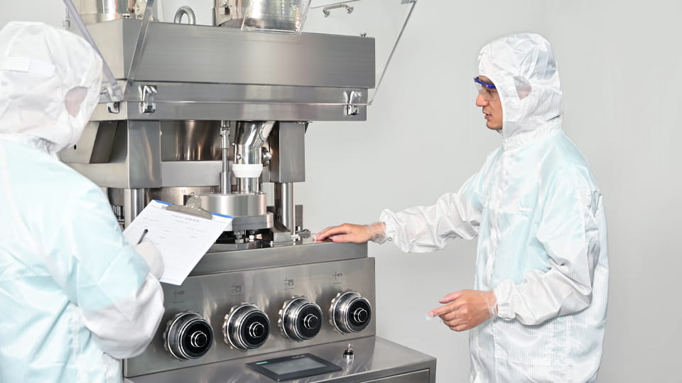 Workers operating the tablet press machine