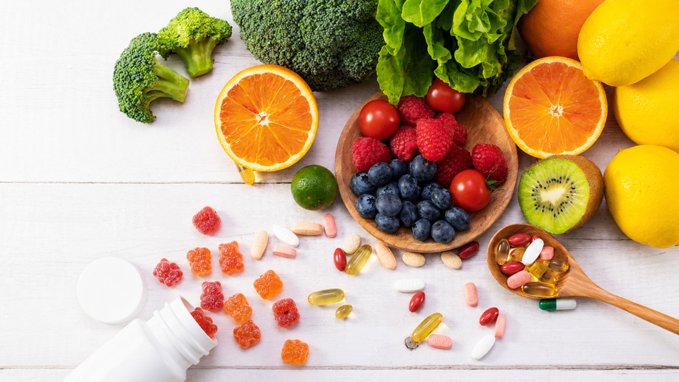 Fruit, wooden spoons, vitamin gummies and pills on the table