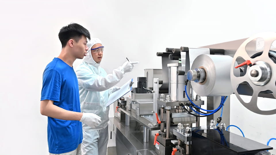 Technologist expert in protective uniform taking parameters from blister machine in Pharma industry
