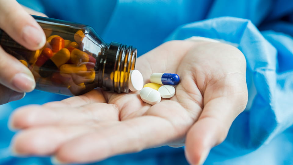 The nurse pours the tablets and capsules out of the medicine bottle
