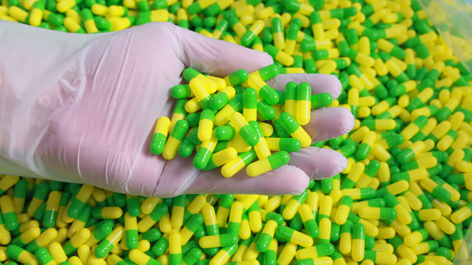 hand grabs a handful of capsules