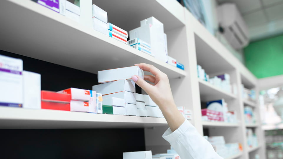 pharmacist hand taking medicine box from the shelf in drug store