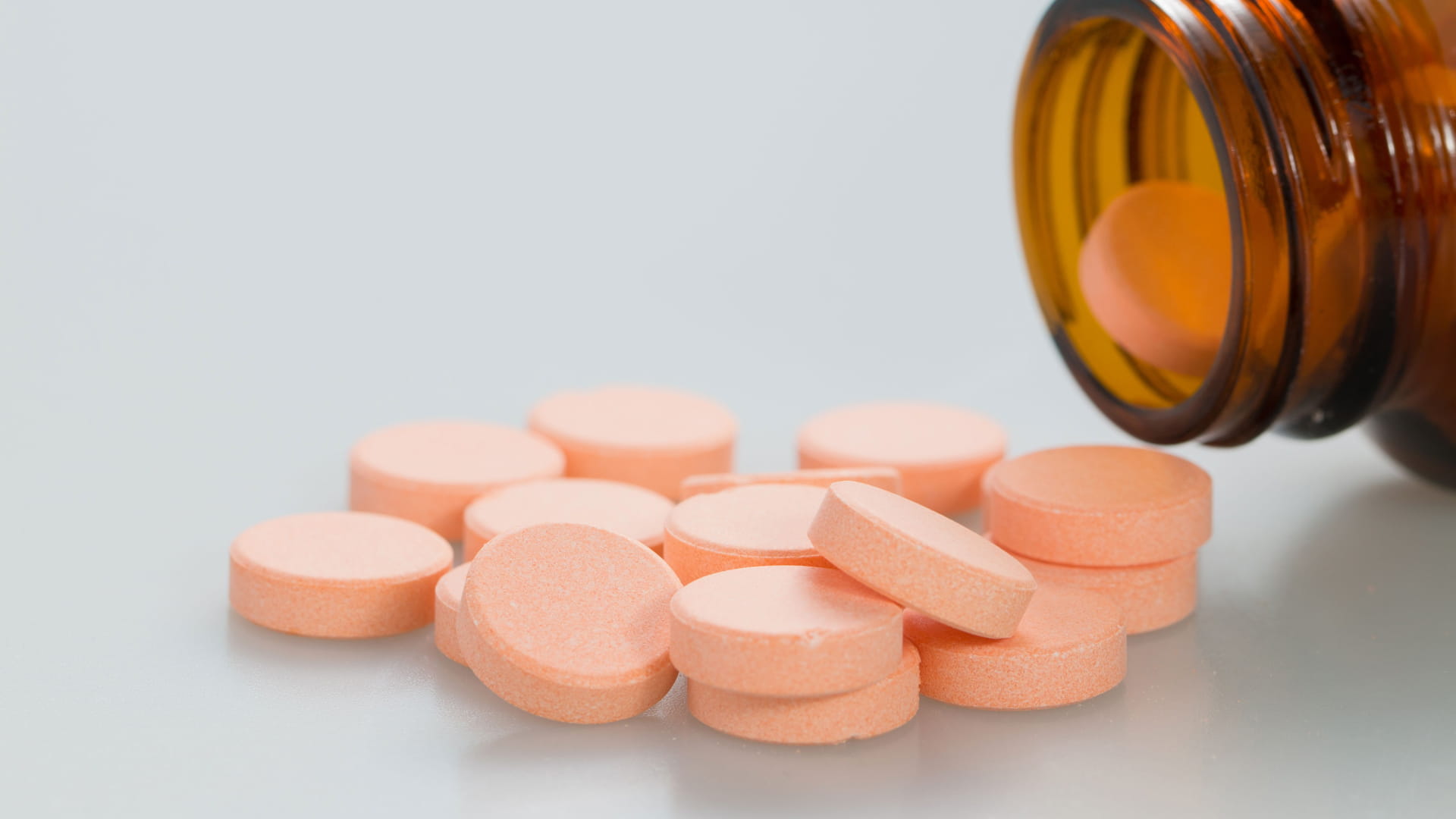 Orange chewable tablets pour from pill bottle