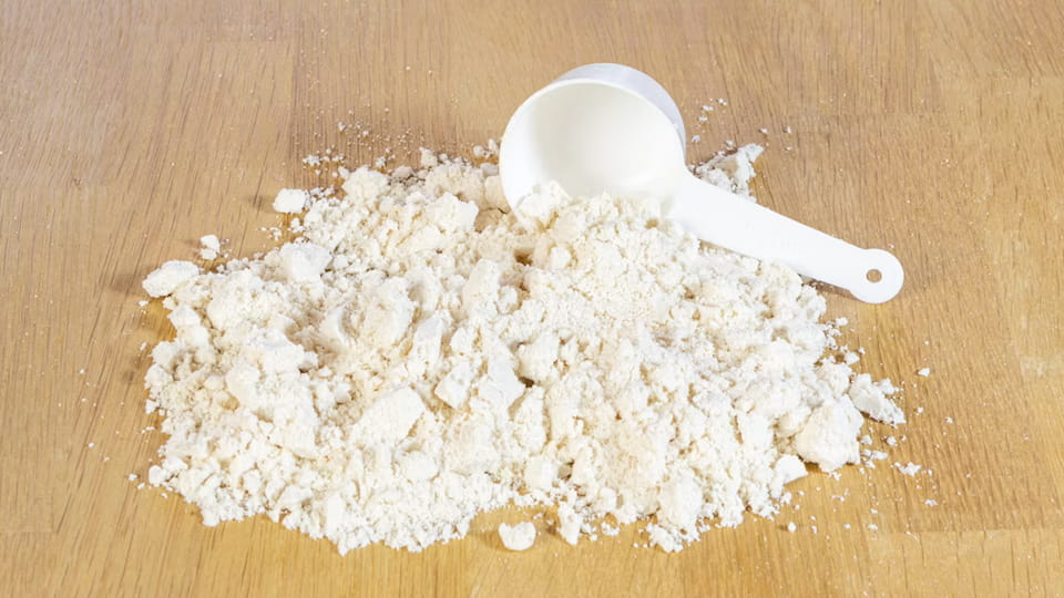 Protein powder on a wooden table with a white spoon