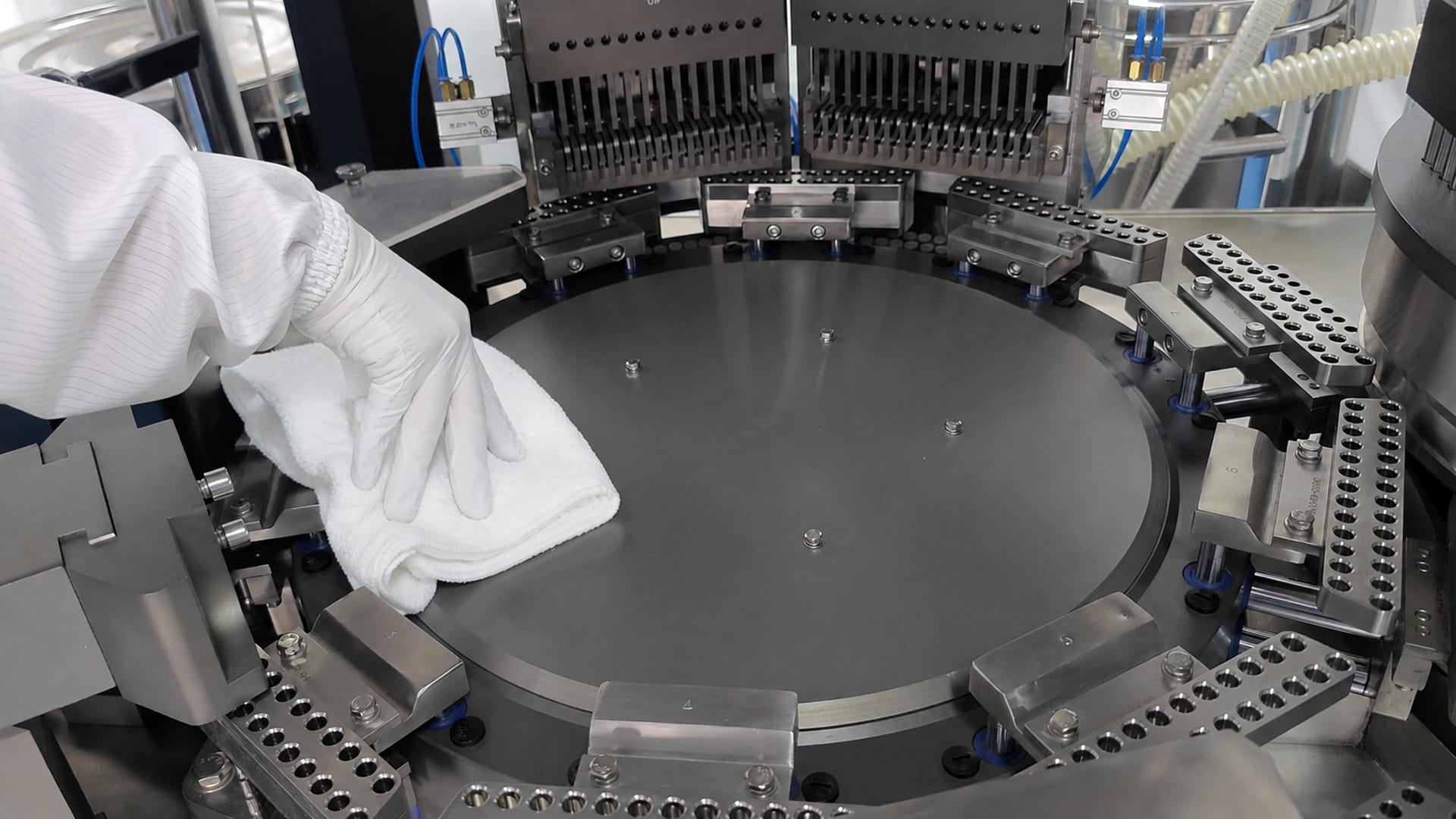 Operator wearing cleanroom garments cleaning the rotary table of a pharmaceutical capsule filling machine during pharmaceutical cleaning validation to prevent cross-contamination
