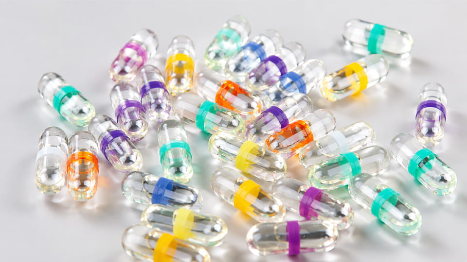Transparent hard capsules with colored sealing bands around the cap-body joint, illustrating capsule band sealing.