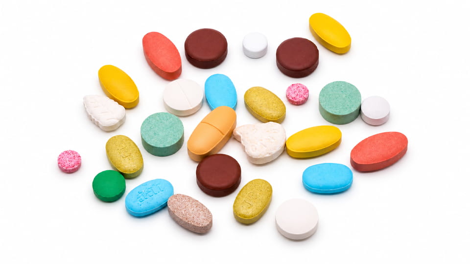 Assorted pharmaceutical tablets in different shapes, サイズ, 色, and thicknesses, illustrating physical tablet quality attributes in tablet manufacturing.