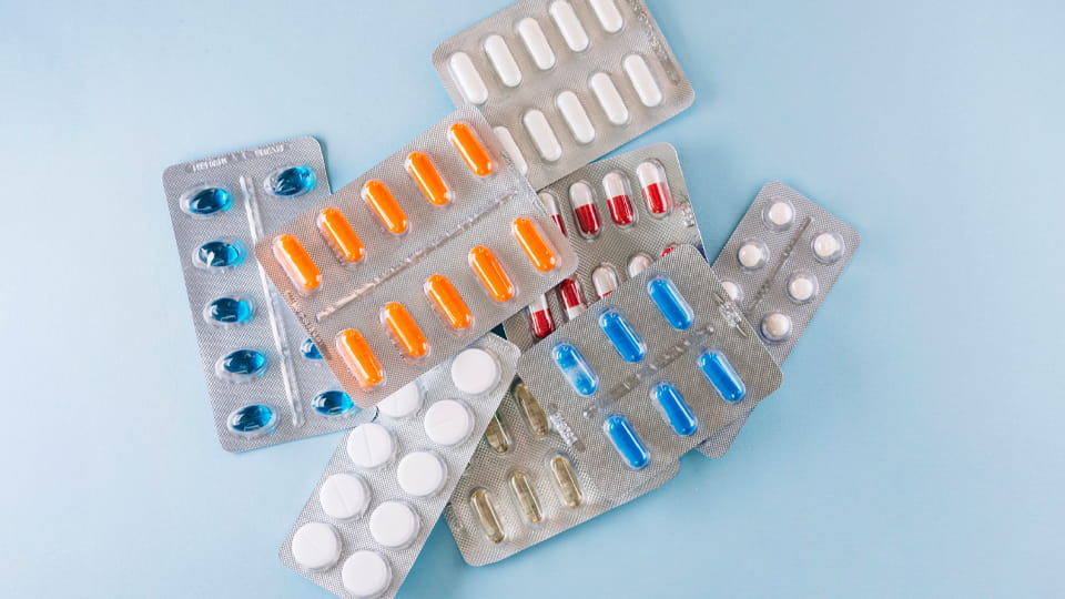 Tablets and capsules in multiple blister packs, illustrating pharmaceutical product and blister packaging material compatibility.