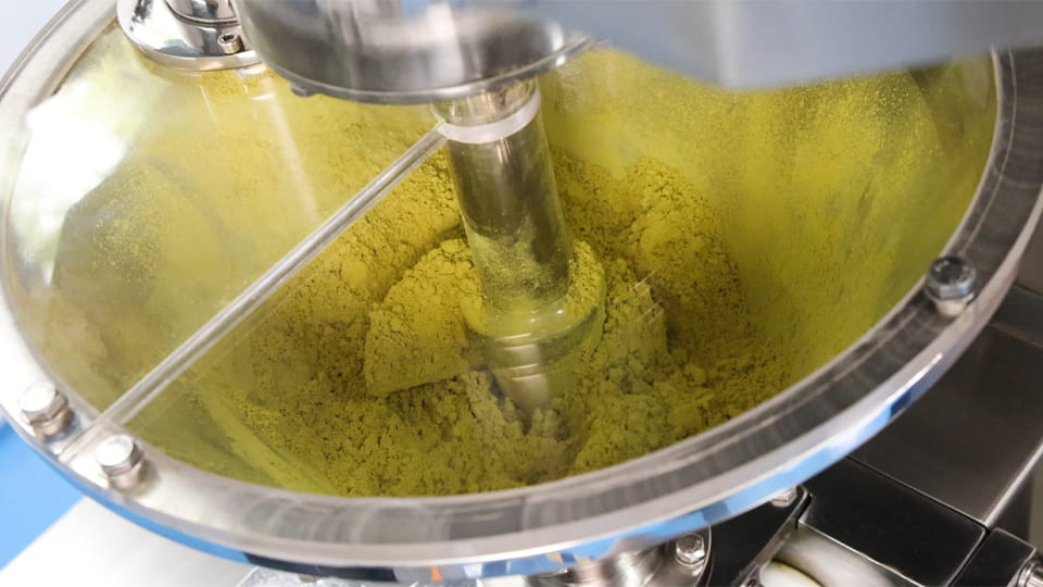 Screw feeder inside a dry granulator handling powder during pharmaceutical formulation preparation.