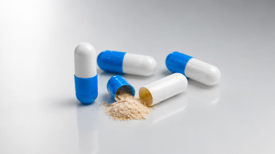 Blue and white capsules with powder filling, illustrating factors that determine capsule fill weight.