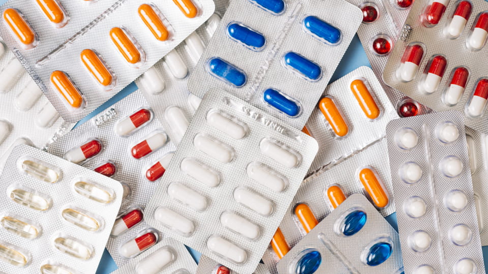 Pharmaceutical blister packs containing tablets and capsules in different shapes and colors, illustrating common blister packaging formats.